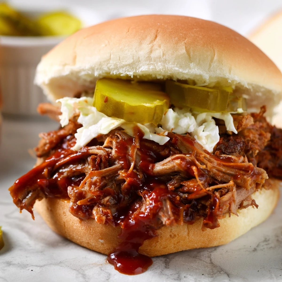 Juicy pulled pork sandwich piled high on a fluffy bun, ready to eat and dripping with BBQ sauce.