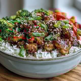 Glossy Honey Garlic Chicken Bowl featuring tender glazed chicken thighs, fluffy jasmine rice, and colorful stir-fried vegetables, garnished with fresh green onions and sesame seeds.