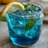 Vibrant butterfly pea flower lemonade changing colors over ice.