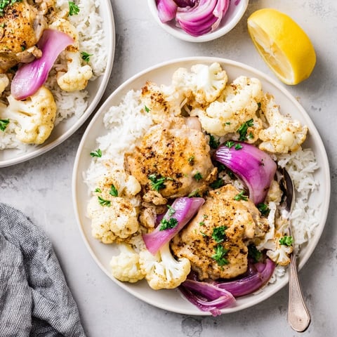 Golden-brown roasted cauliflower chicken sheet pan topped with fresh cilantro and lemon wedges, served over fluffy basmati rice.