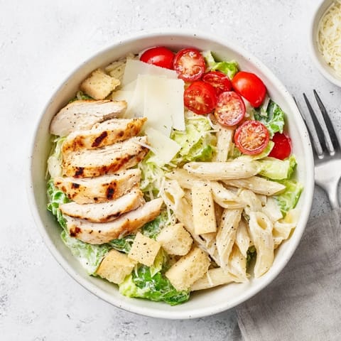 A vibrant Caesar Pasta Chicken Bowl with grilled chicken slices, crisp romaine, and pasta tossed in creamy Caesar dressing.
