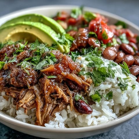 A hearty, gluten-free Mexican-style bowl featuring slow-cooked pork, pinto beans, and lime wedges ready for squeezing.