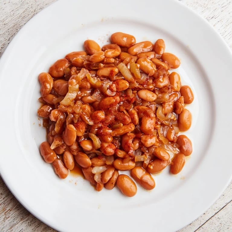 A close-up of savory, glossy Baked Beans, perfect for serving alongside your favorite BBQ dishes.
